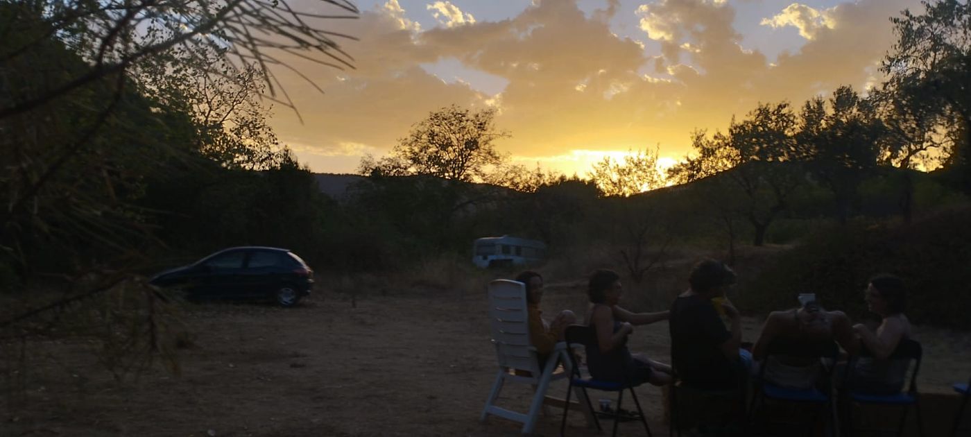 Sonnenuntergang über dem Gelände, Menschen sitzen zusammen